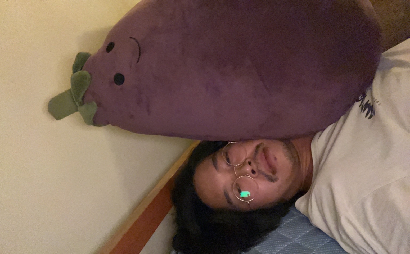 DJ Nasutaro laying down with a large eggplant stuffed animal