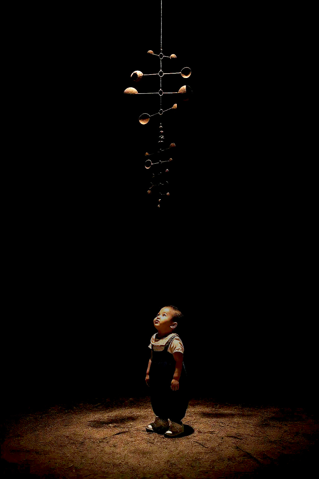 Child gazing at a mobile kinetic sculpture